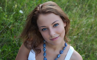 photo of woman wearing blue polished stone necklace and white tank top during daytime
